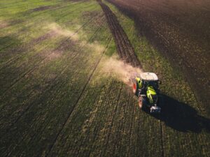 Tractor driving across a field with dust coming up. Photo by Chris Ensminger