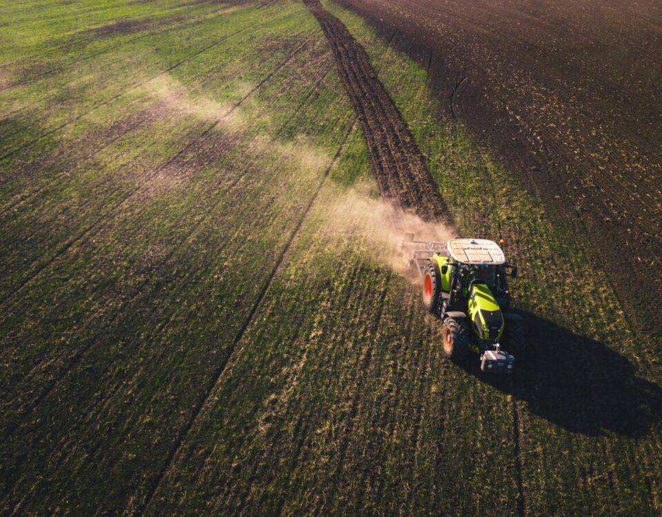 Tractor driving across a field with dust coming up. Photo by Chris Ensminger