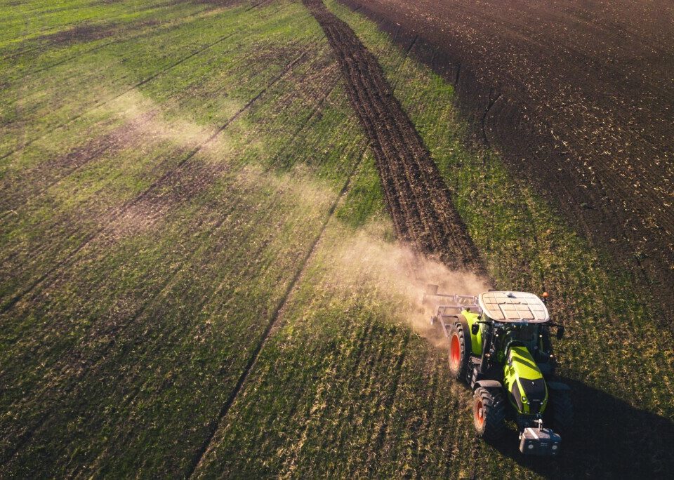 Tractor driving across a field with dust coming up. Photo by Chris Ensminger